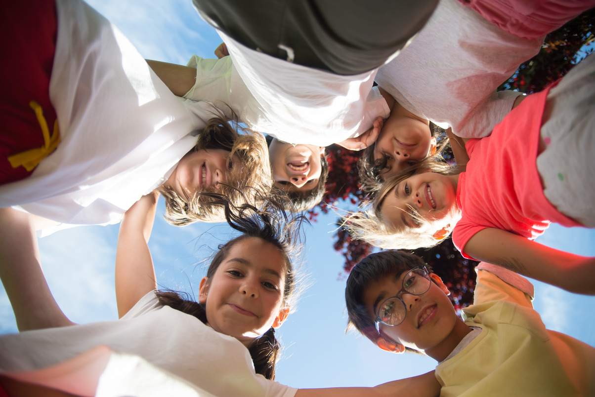 a group of children standing in a circle with their arms around each other