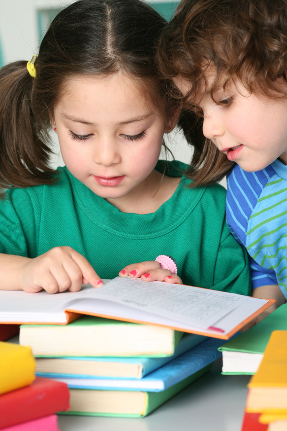 two young children are looking at a book