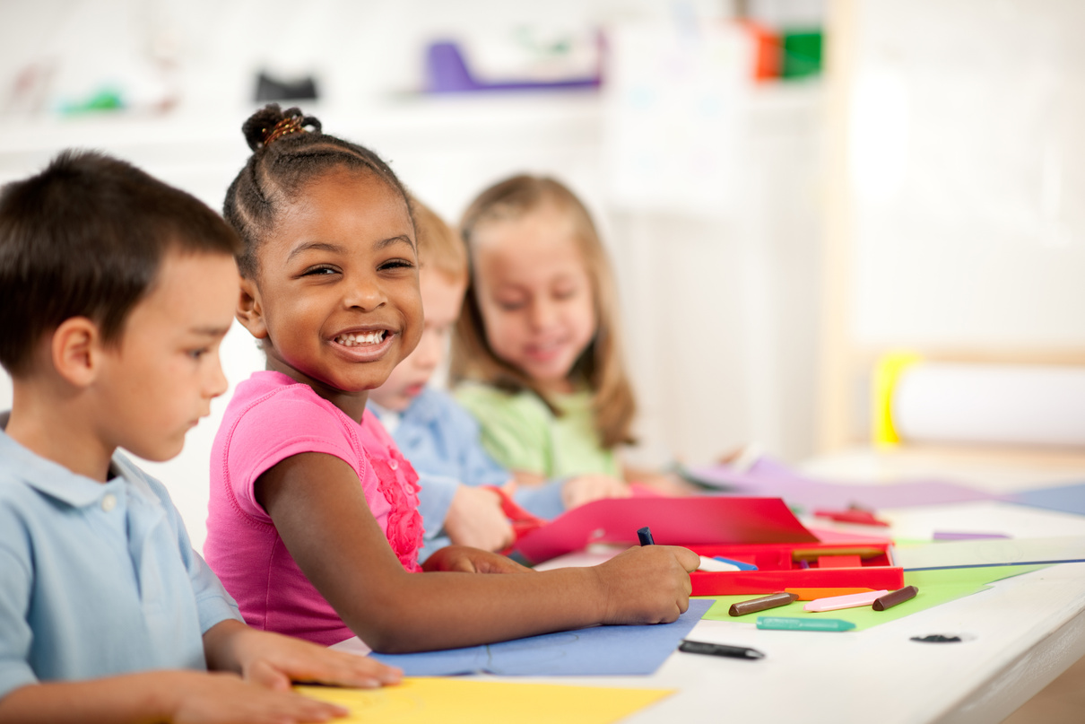 a group of children sitting at a table with paper