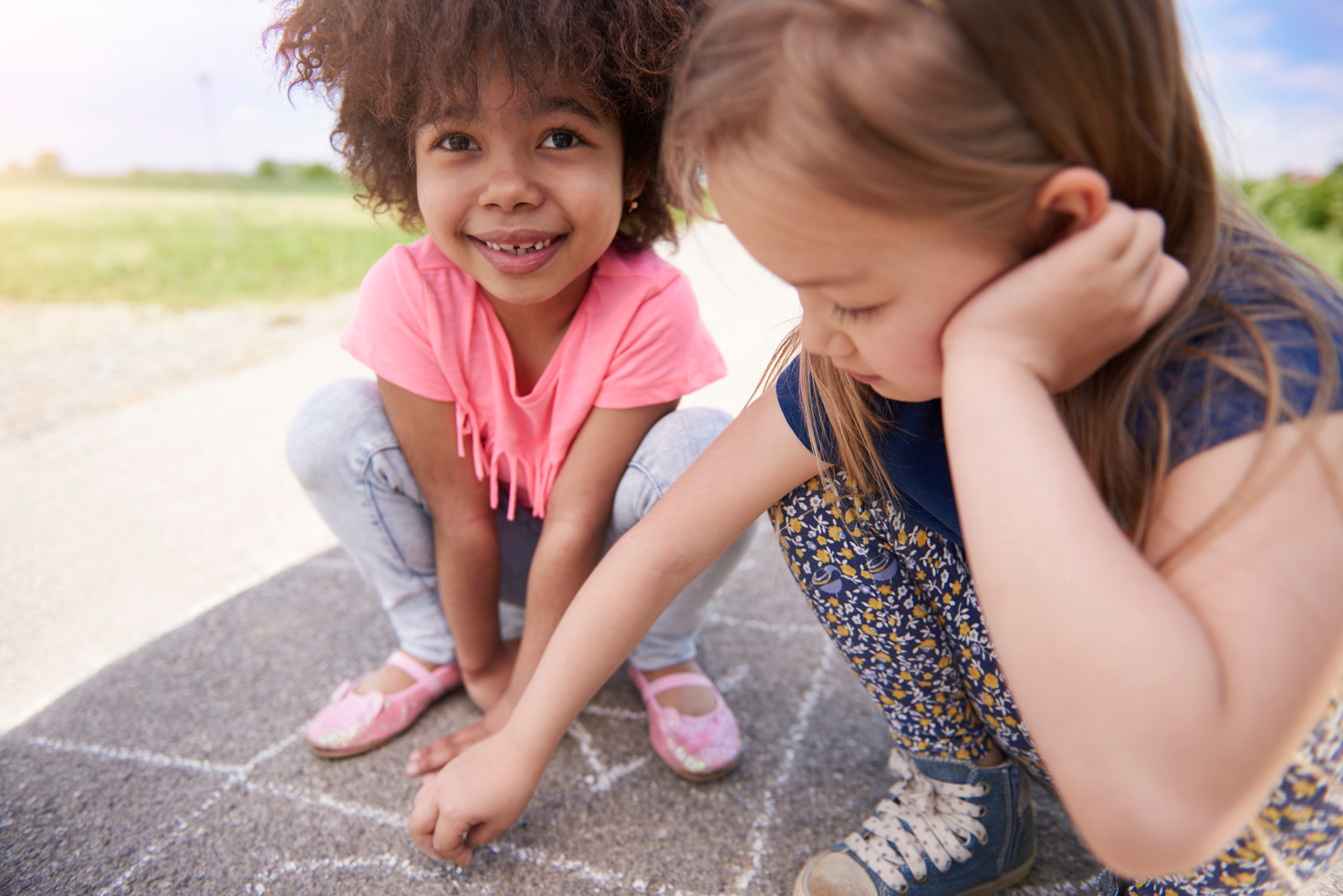 two young girls playing with chalk on the ground